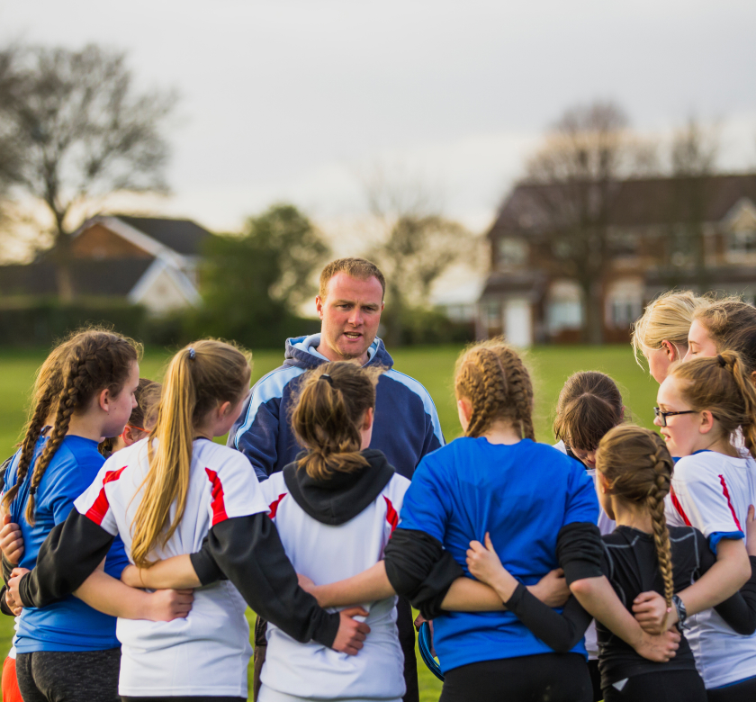 Image (An NLS coach handing a marker to a group of primary school children sitting on the grass) (1)